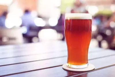 A pint of beer on a table at an outdoor craft beer festival.
