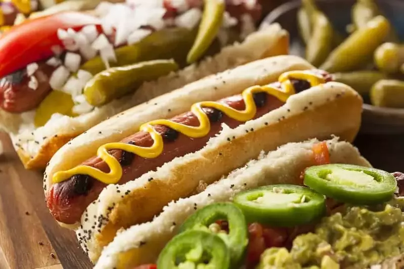 A row of gourmet hot dogs with lots of toppings.