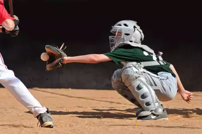 Teenage catcher catching a baseball.