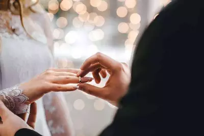 man putting ring on woman's finger at wedding