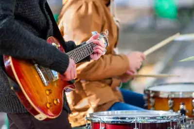 A guitarist and drummer performing at an outdoor concert.