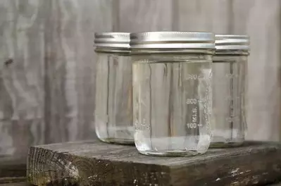 Three mason jars filled with clear moonshine.