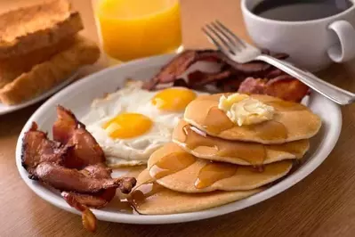 Pancakes, eggs, and bacon on a plate.