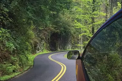 Car driving on a scenic road to a Great Smoky Mountains National Park visitor center.
