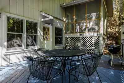 Misty Mountain Hop – a 2-bedroom, 2-bath Smoky Mountain cabin in Cobbly Nob Resort with screened-in hot tub, wrap-around decks, wood-burning fireplace, and access to pools, pickleball, and golf.