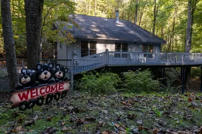 Misty Mountain Hop – a 2-bedroom, 2-bath Smoky Mountain cabin in Cobbly Nob Resort with screened-in hot tub, wrap-around decks, wood-burning fireplace, and access to pools, pickleball, and golf.