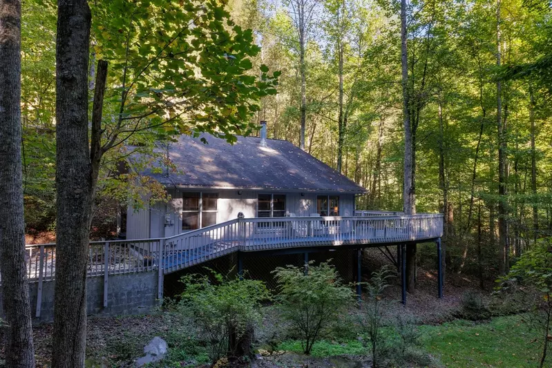 Misty Mountain Hop – a 2-bedroom, 2-bath Smoky Mountain cabin in Cobbly Nob Resort with screened-in hot tub, wrap-around decks, wood-burning fireplace, and access to pools, pickleball, and golf.