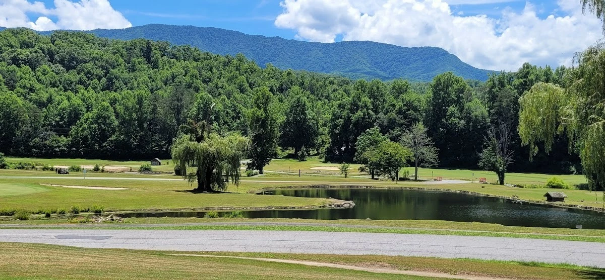 Misty Mountain Hop – a 2-bedroom, 2-bath Smoky Mountain cabin in Cobbly Nob Resort with screened-in hot tub, wrap-around decks, wood-burning fireplace, and access to pools, pickleball, and golf.
