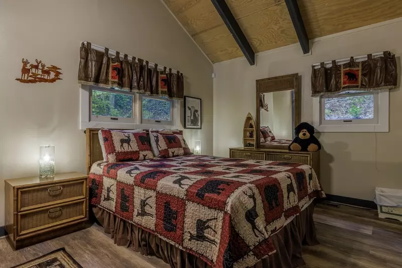 Misty Mountain Hop – a 2-bedroom, 2-bath Smoky Mountain cabin in Cobbly Nob Resort with screened-in hot tub, wrap-around decks, wood-burning fireplace, and access to pools, pickleball, and golf.