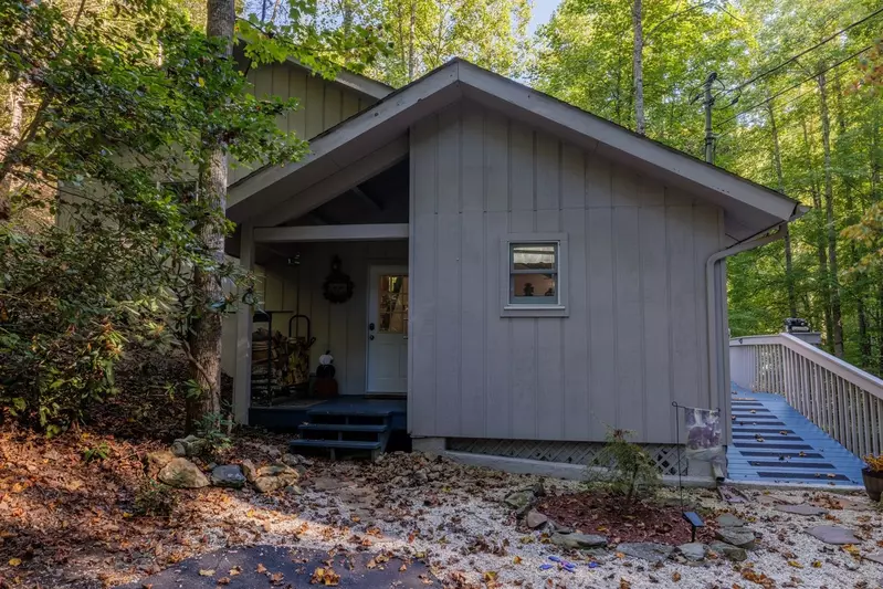 Misty Mountain Hop – a 2-bedroom, 2-bath Smoky Mountain cabin in Cobbly Nob Resort with screened-in hot tub, wrap-around decks, wood-burning fireplace, and access to pools, pickleball, and golf.