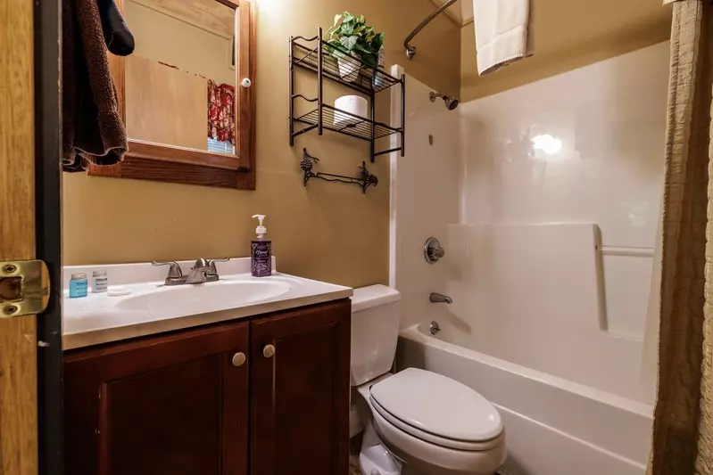 Misty Mountain Hop – a 2-bedroom, 2-bath Smoky Mountain cabin in Cobbly Nob Resort with screened-in hot tub, wrap-around decks, wood-burning fireplace, and access to pools, pickleball, and golf.