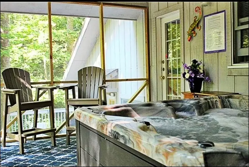 Misty Mountain Hop – a 2-bedroom, 2-bath Smoky Mountain cabin in Cobbly Nob Resort with screened-in hot tub, wrap-around decks, wood-burning fireplace, and access to pools, pickleball, and golf.
