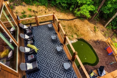 Spacious deck with outdoor seating, nature views, string lights, fire pit, mini golf, and hot tub.