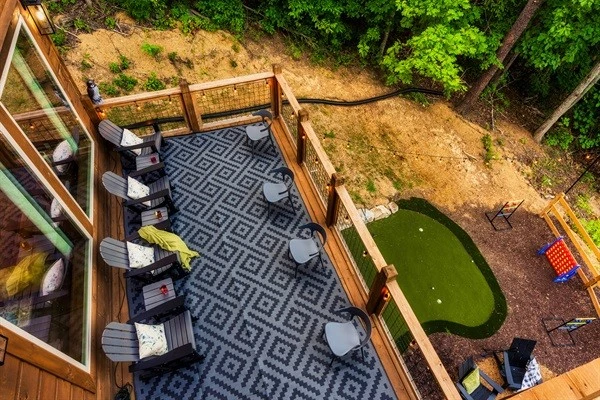 Spacious deck with outdoor seating, nature views, string lights, fire pit, mini golf, and hot tub.