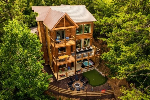 Luxury cabin with multiple decks , hot tub, and backyard with string lights, fire pit and mini golf