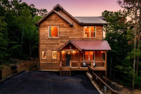 Luxury cabin with multiple decks with string lights, hot tub, and backyard with fire pit and mini golf