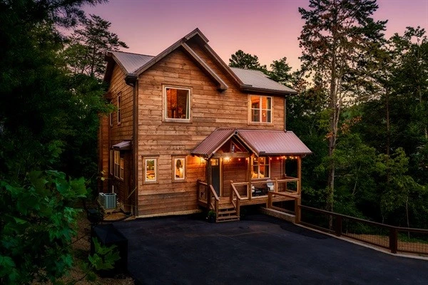 Luxury cabin with multiple decks with string lights, hot tub, and backyard with fire pit and mini golf