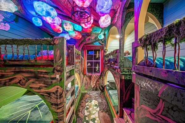 Downstairs bunk room. The forest canopy ceiling glows and shimmers with magical colors. Magical forest dreamscape: two queens and four XL twin beds. Plus a hobbit door!