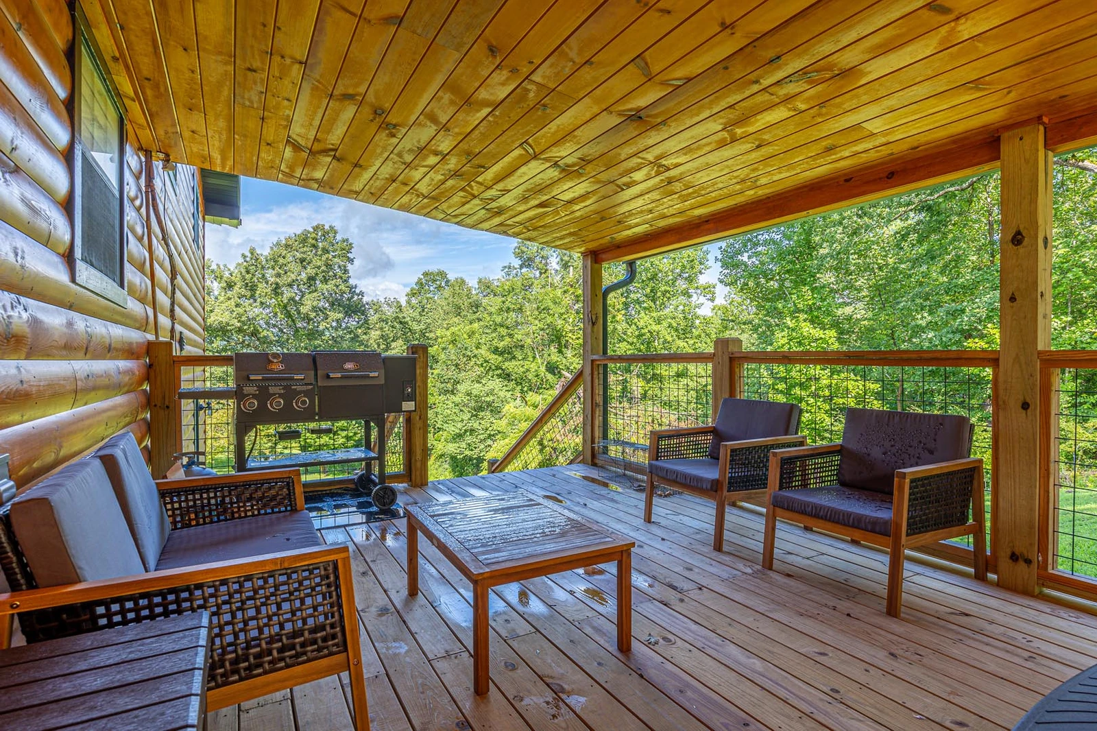 Outdoor seating and gas grill under the cabin's porch.