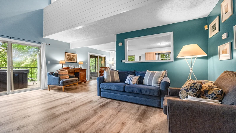 Your relaxing Gatlinburg chalet's living room with large glass doors looking out over a forest setting.