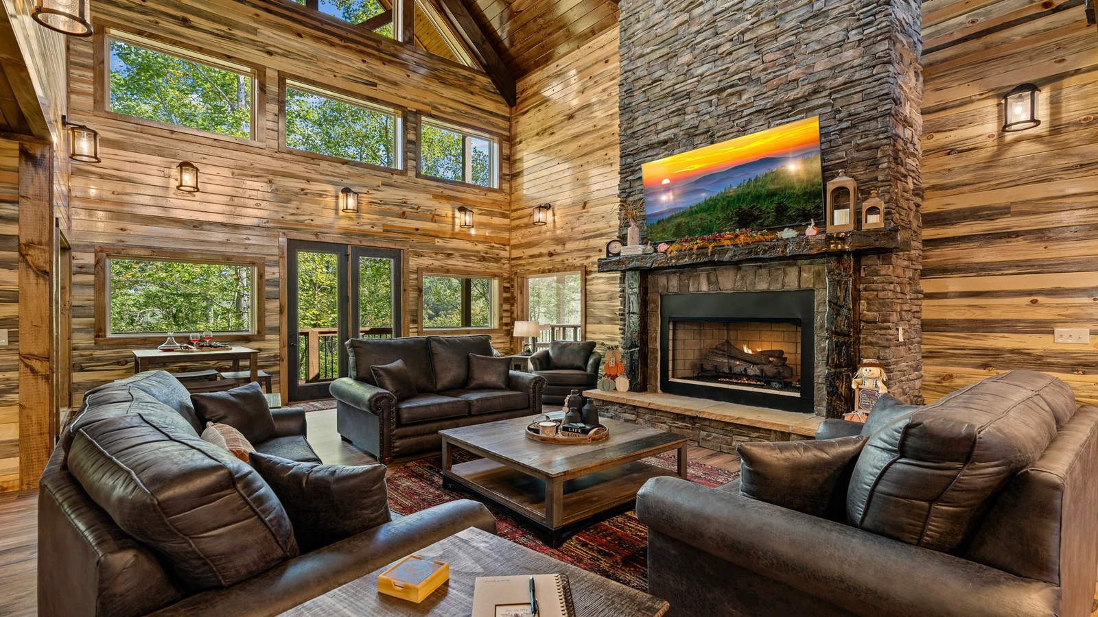 Relax in the large open living room with massive fireplace and large windows overlooking a forest setting.