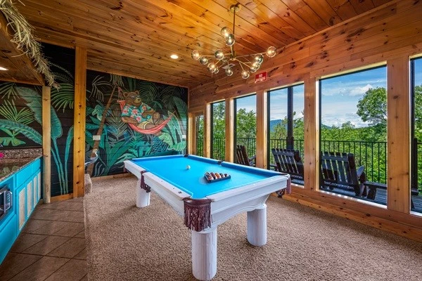 Game room with large windows offering a scenic mountain views and access to a balcony with rocking chairs