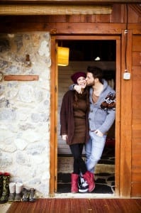 Couple standing by the cabin door with guy kissing girl on the cheek