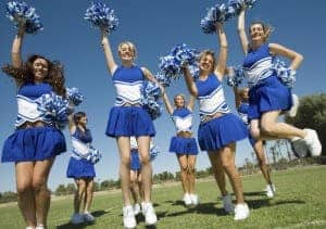 Young cheerleaders cheering with pom poms
