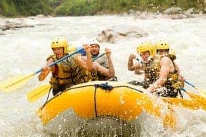 Group of men and women white water rafting