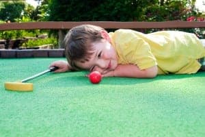 Kid laying down on mini golf course