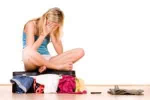 Woman sitting on her suitcase stressed