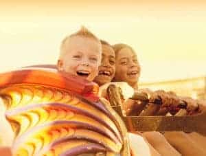 Kids riding roller coaster in the sunset