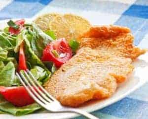 Fried catfish fillet with salad and orange slices on the side