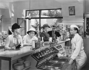 Black and white picture of people sitting at a soda fountain