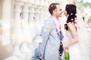 Just married couple kissing with pink flower petals
