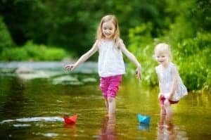 Sisters playing with paper boats in a river