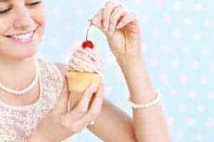 Woman eating cupcake with a cherry on top