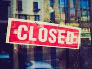 Red closed sign hanging on a glass door