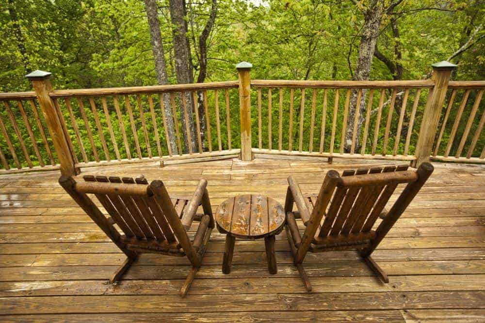 The deck of a cabin with wooded views.