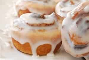 Cinnamon rolls covered in icing on a platter