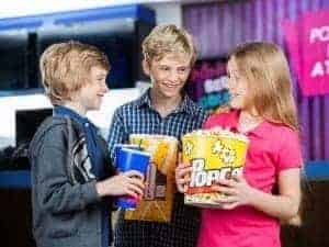 Three kids holding popcorn before seeing a movie together