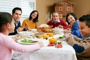 A family at a dining room table eating Thanksgiving dinner.