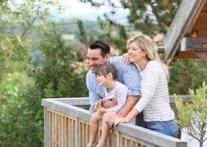 Happy family enjoying the views from the deck of their log cabin.