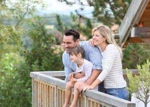 Happy family enjoying the views from the deck of their log cabin.