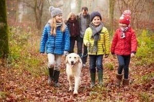 Happy family walking with their pet dog in the woods in the fall.