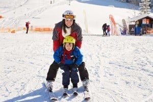 A mother and her young son going skiing.