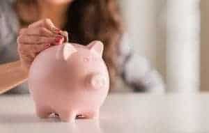 Woman putting a coin in a piggy bank.
