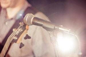 Closeup of a microphone and a guitar player on stage.