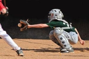 Teenage catcher catching a baseball.