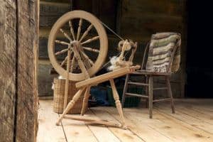 A spinning wheel with yarn in an old cabin.